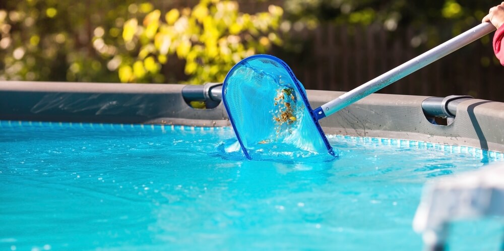 skimming cloudy pool water with leaves from pool